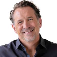 Smiling portrait of Mark Kohler in a dark shirt against a white background