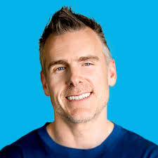 Headshot of Dan Martell smiling against a bright blue background